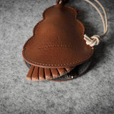 Brown leather keypouch with a leather string on a gray background