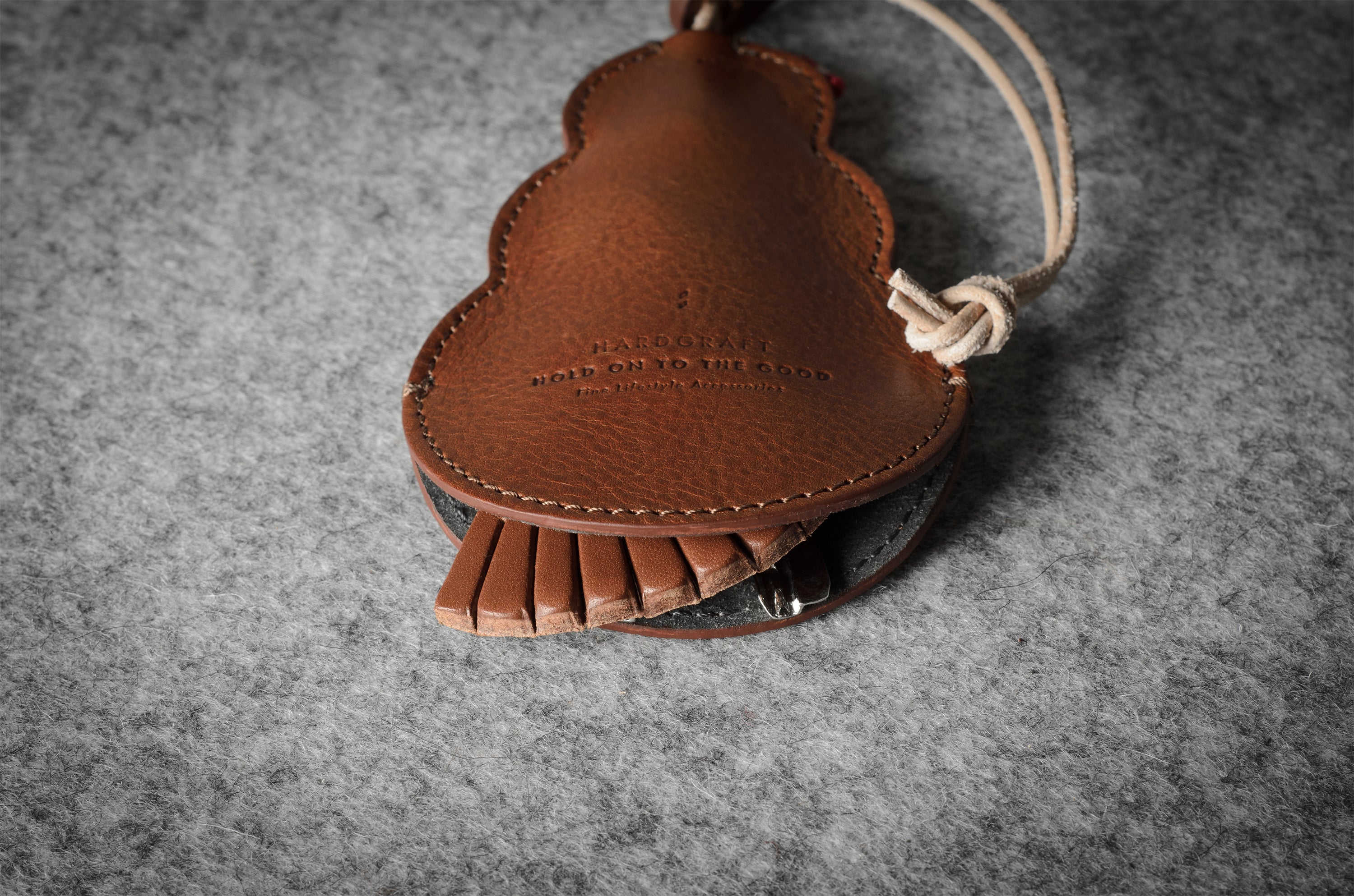 Brown leather keypouch with a leather string on a gray background