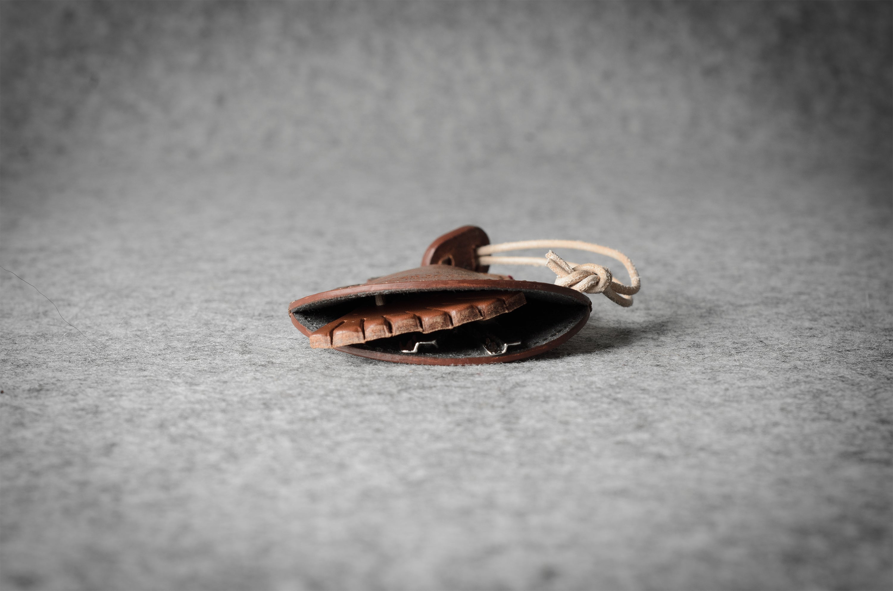 Brown leather keypouch with a leather string on a gray background