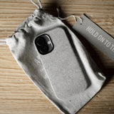 iPhone case in a drawstring bag with a tag on a wooden surface