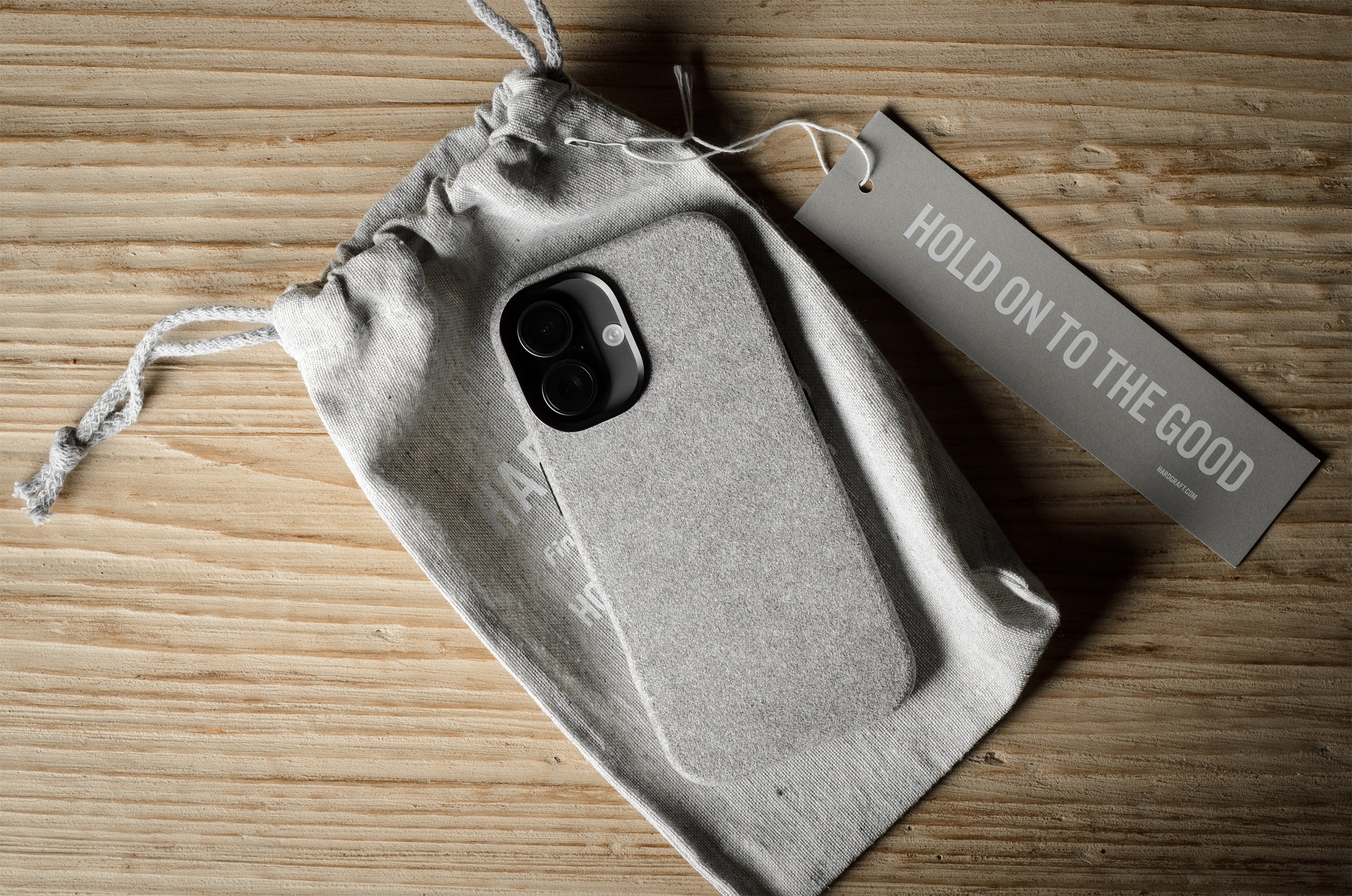 iPhone case in a drawstring bag with a tag on a wooden surface