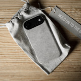 iPhone case in a drawstring bag with a tag on a wooden surface