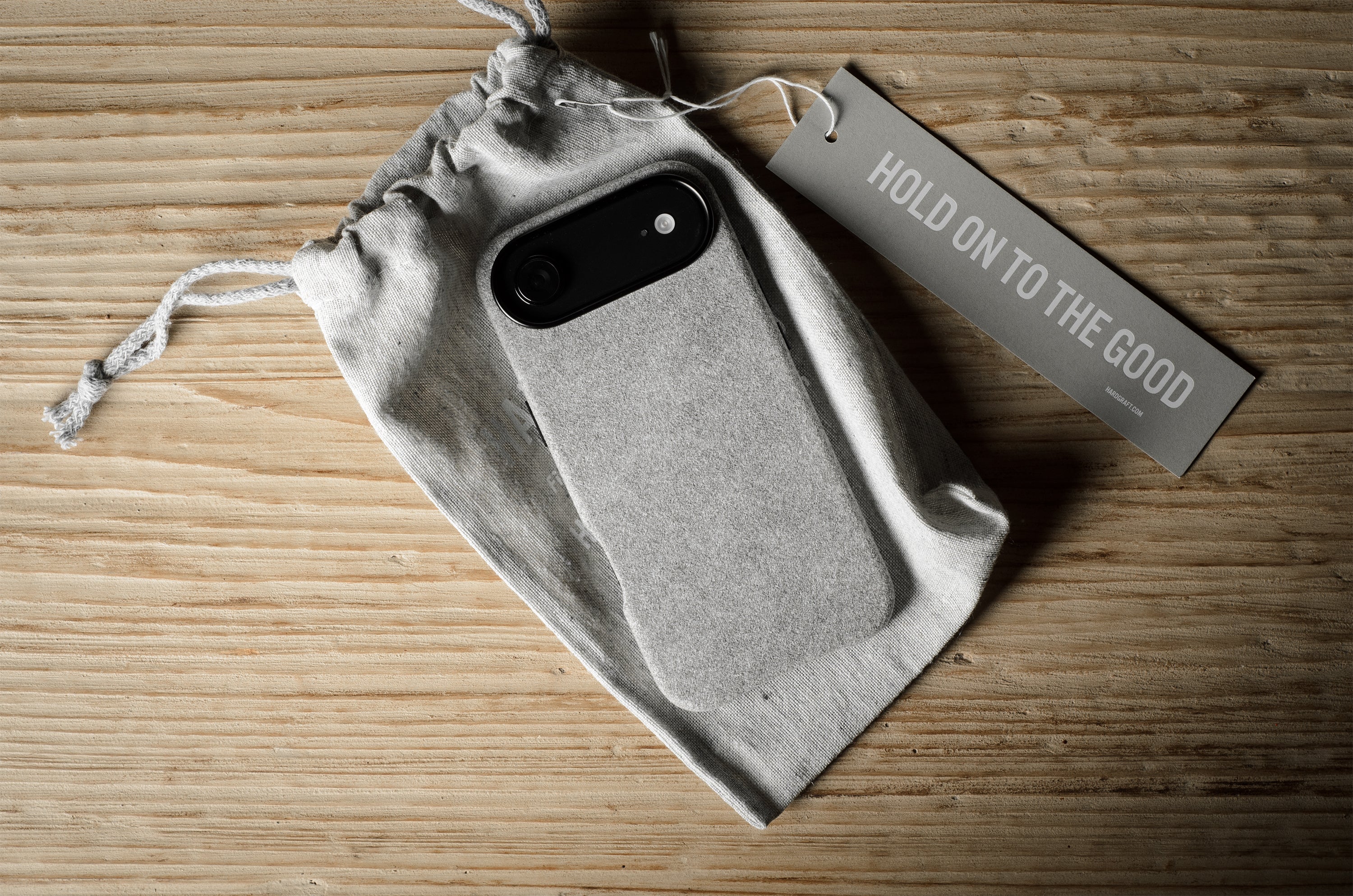iPhone case in a drawstring bag with a tag on a wooden surface
