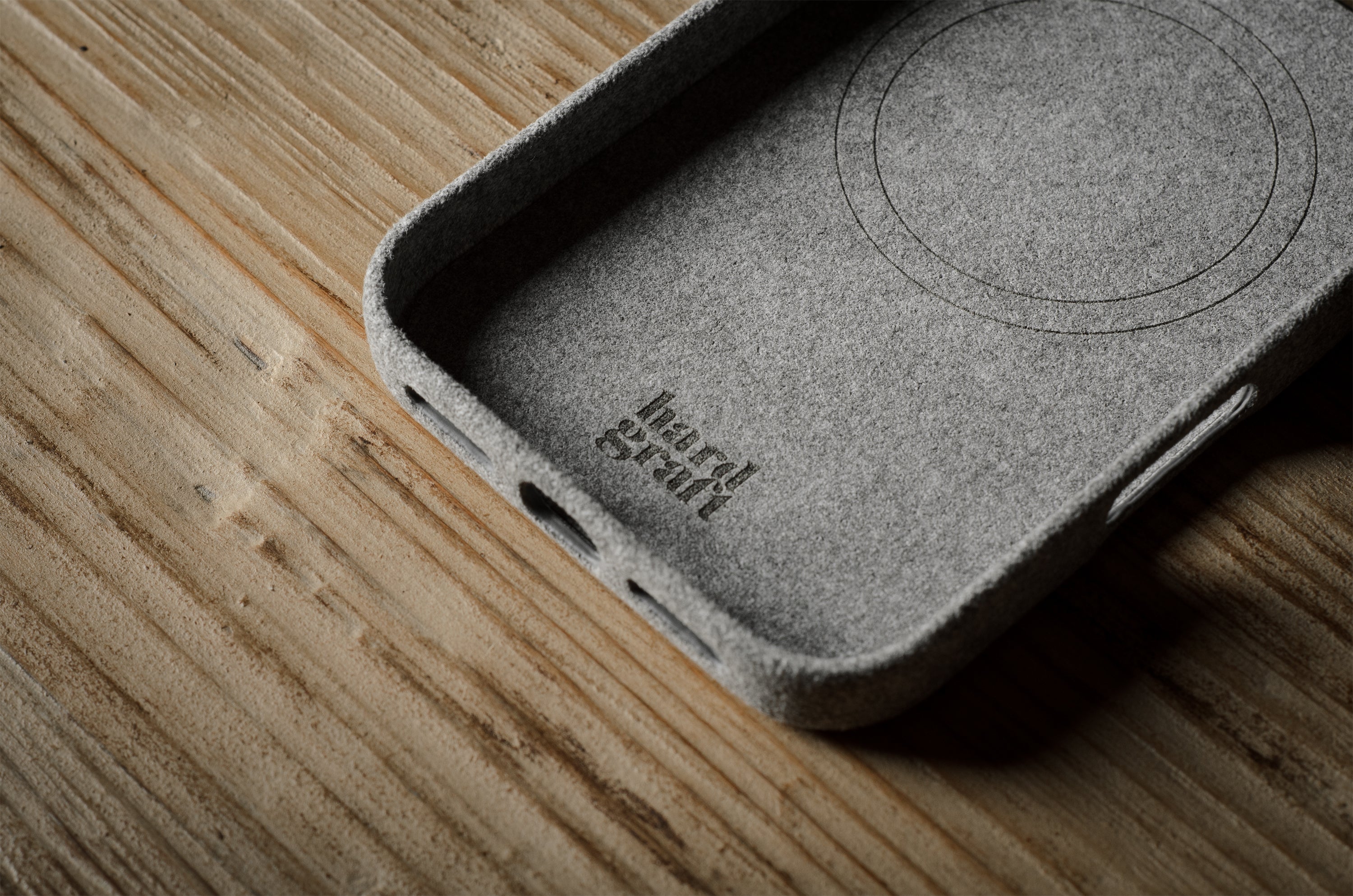 iPhone case on a wooden surface with branding.