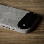 Black iPhone in grey case on a textured gray surface with a wooden background