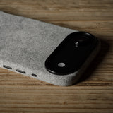 Black iPhone in grey case on a textured gray surface with a wooden background