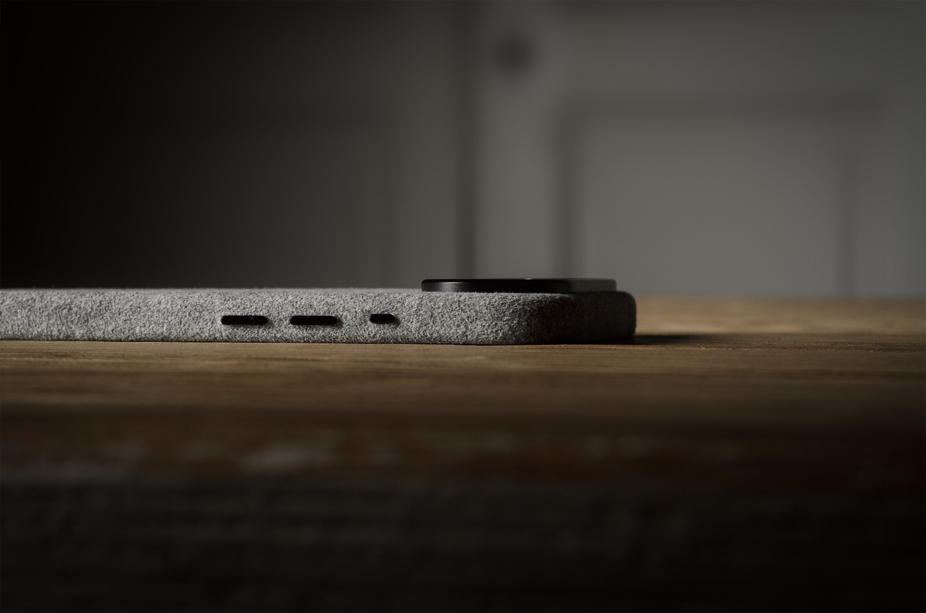 Close-up of a iPhone side profile on a wooden surface with a dark background
