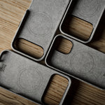 Four gray iphone cases with wooden accents on a wooden surface
