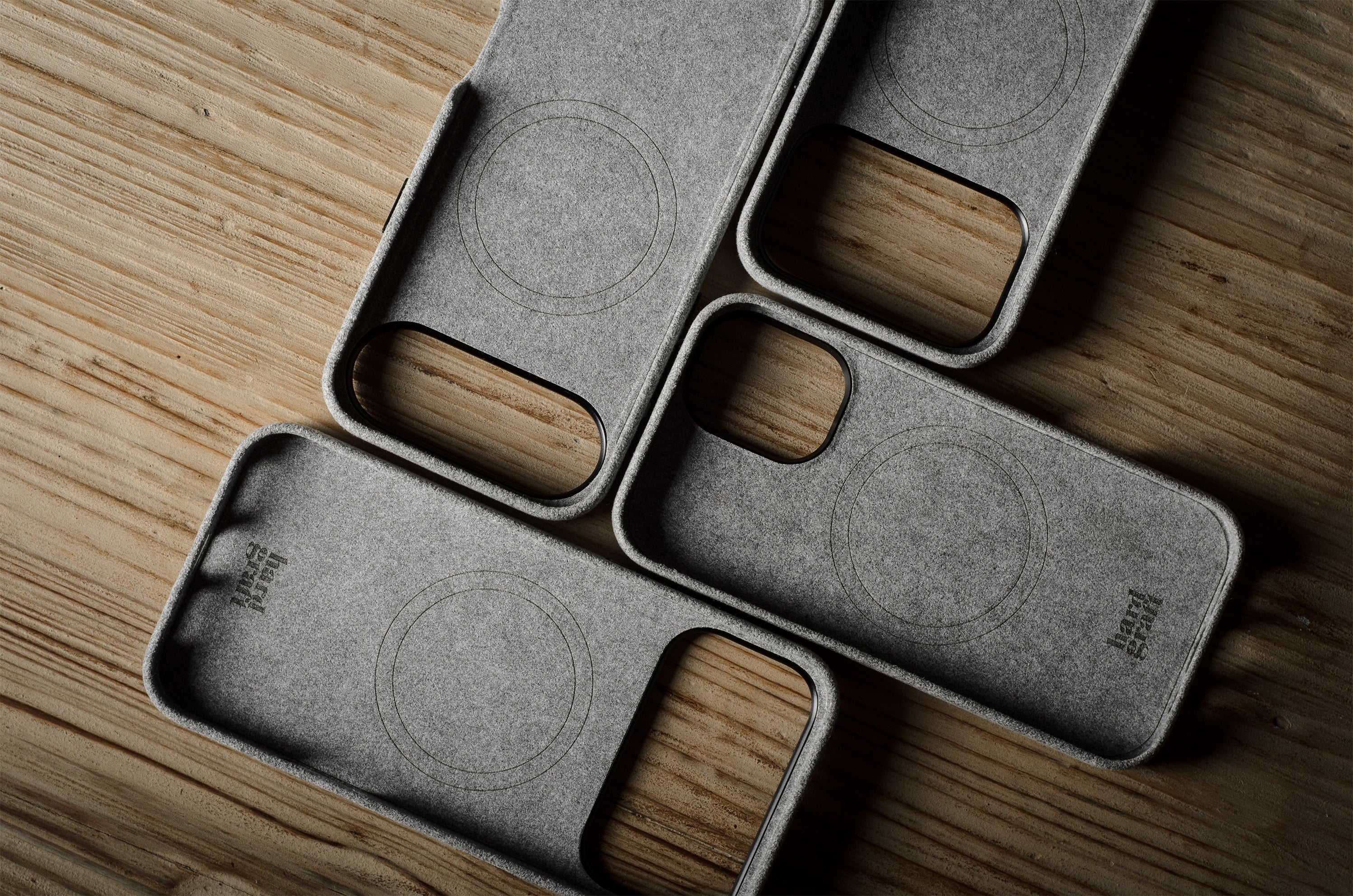 Four gray iphone cases with wooden accents on a wooden surface