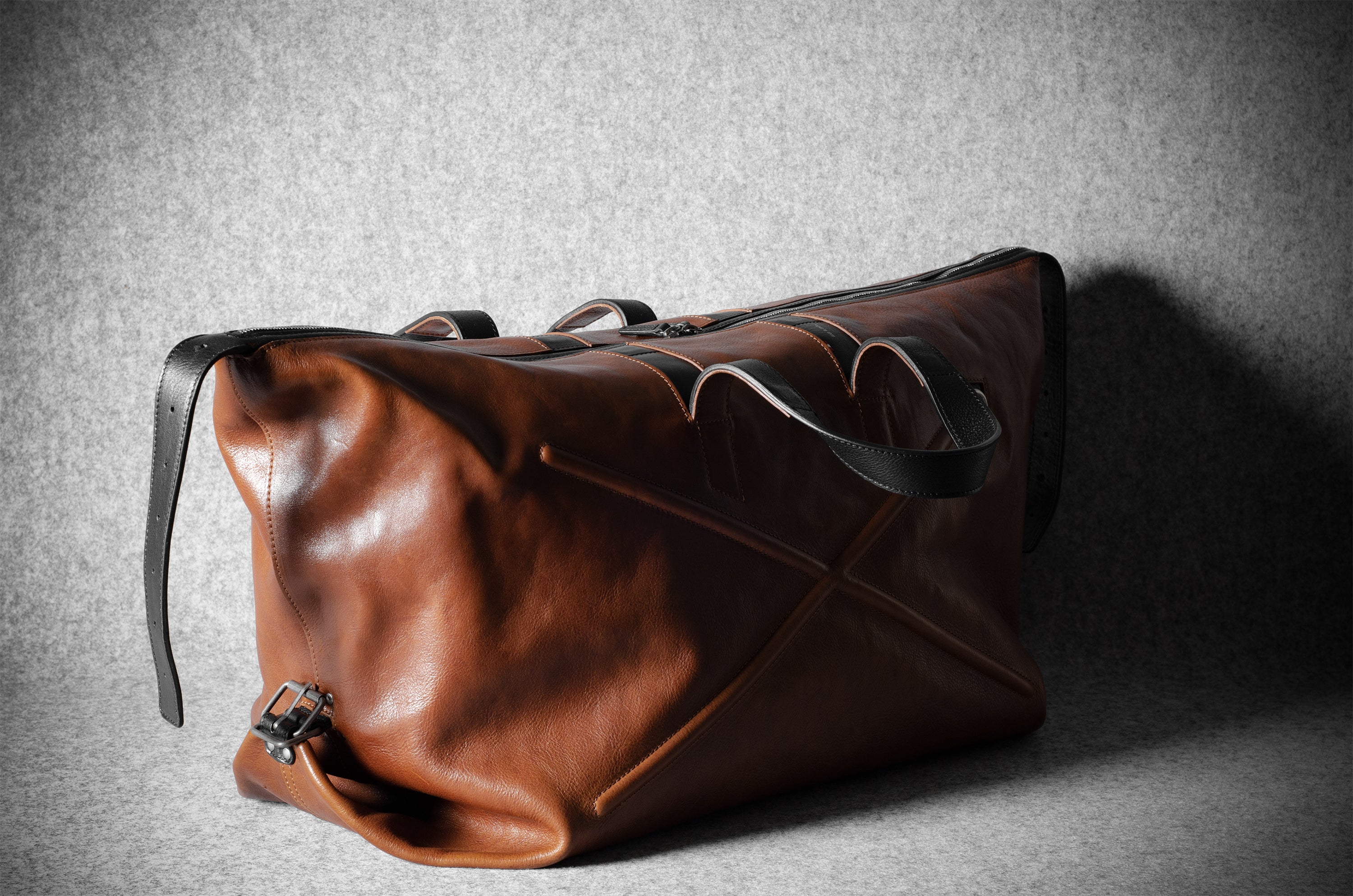 Brown leather duffel bag on a textured gray background