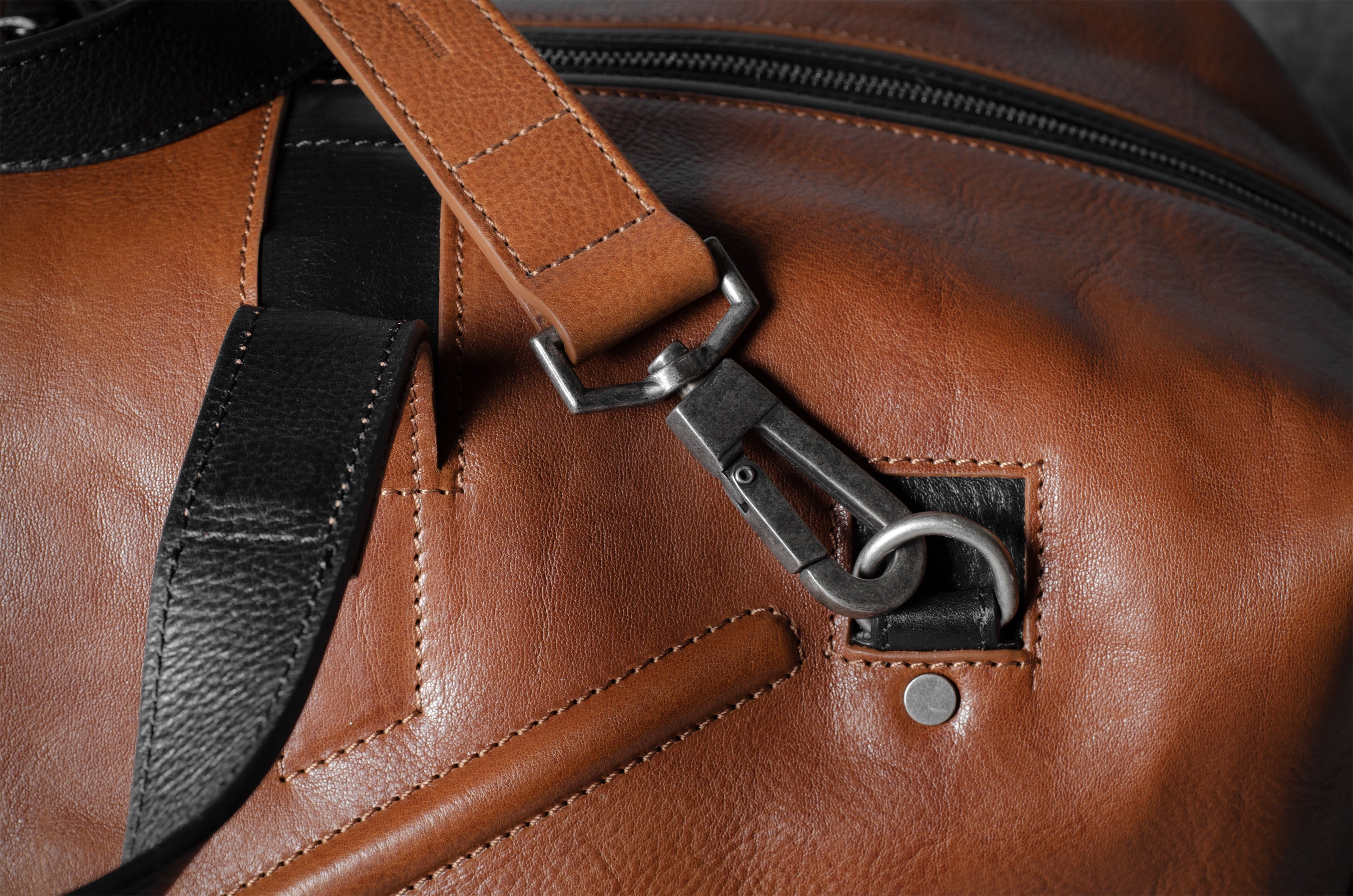 Close-up of a brown leather bag with a metal buckle.