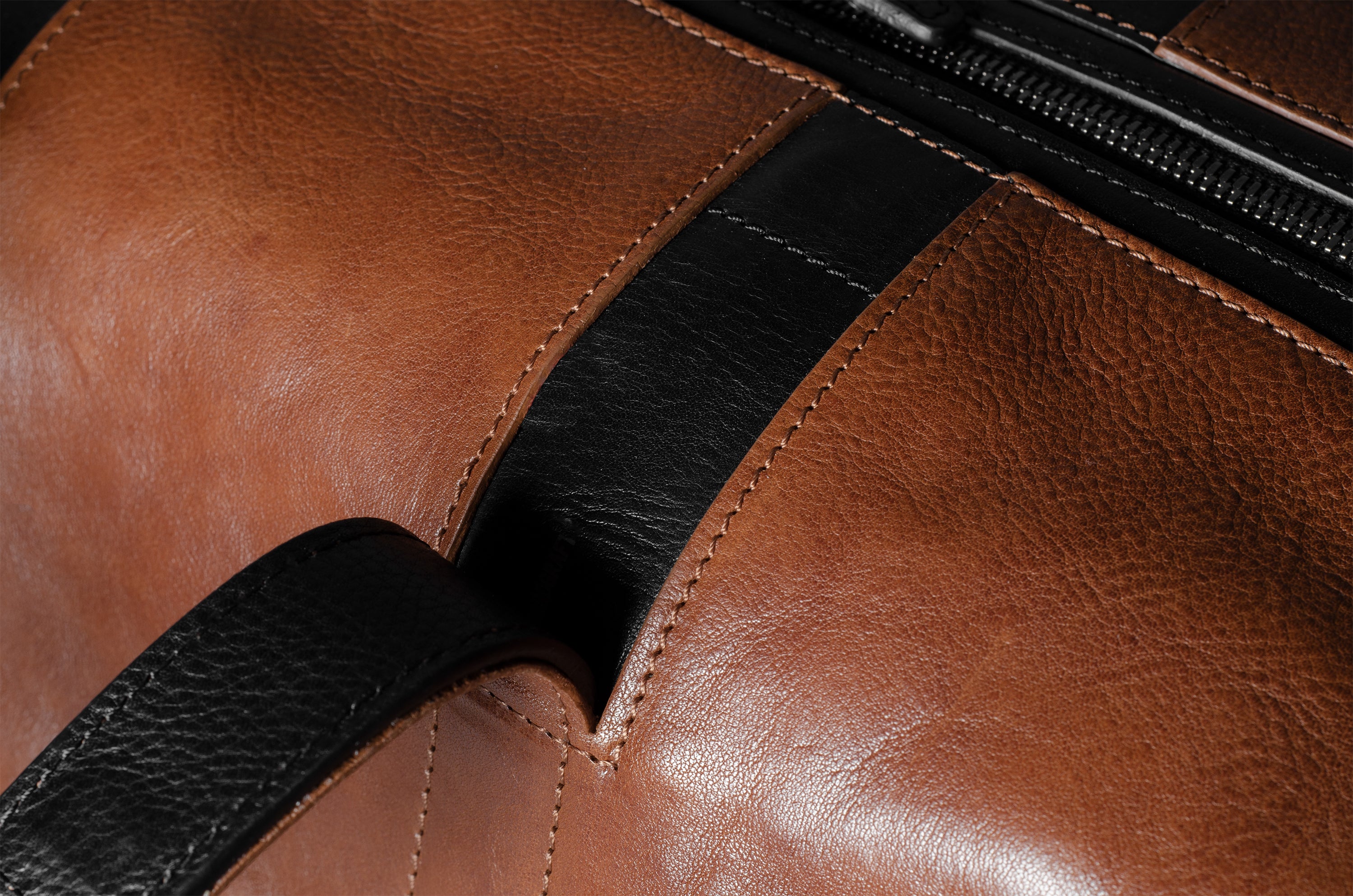 Close-up of a brown leather bag with a black strap