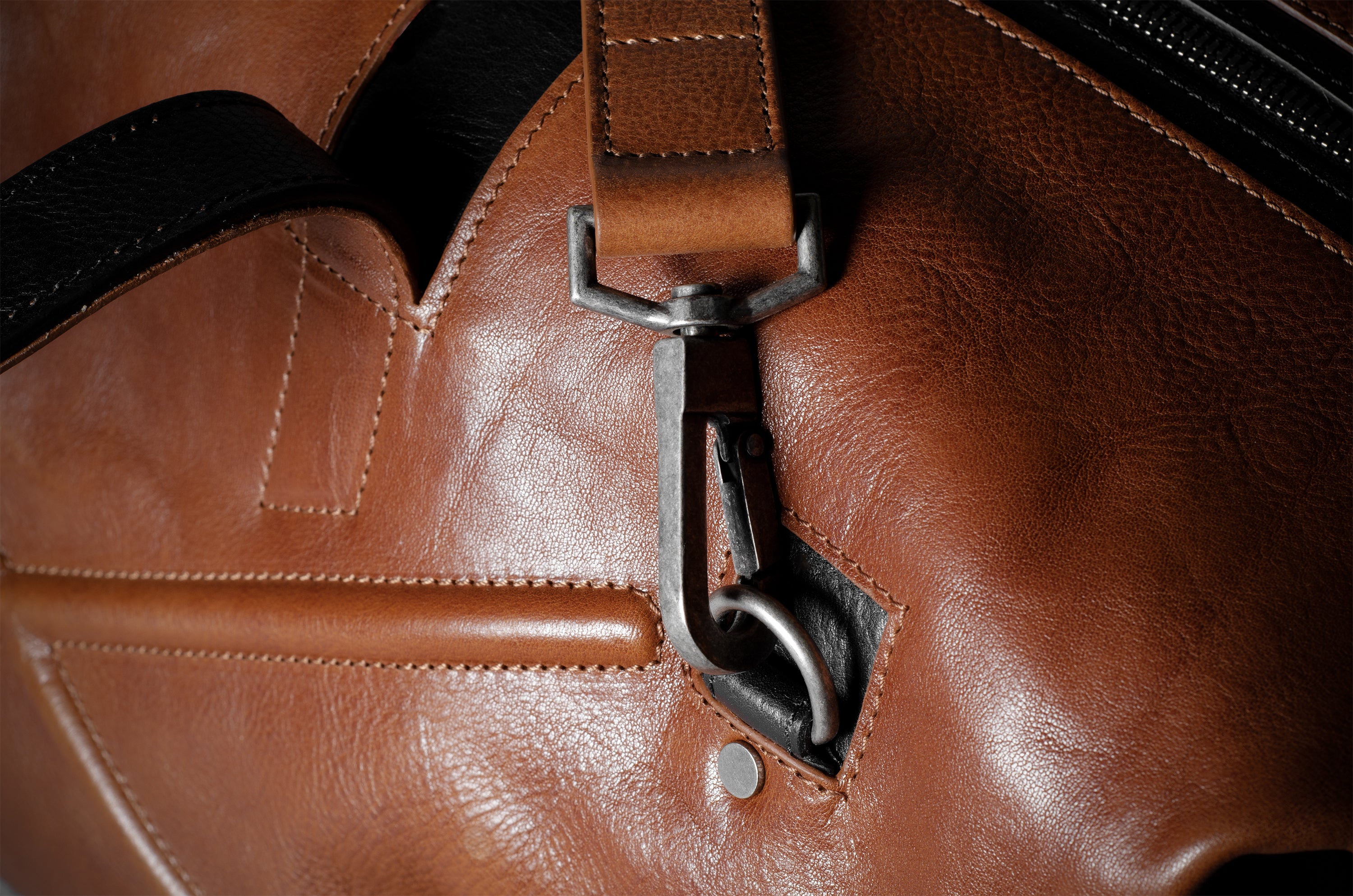 Close-up of a brown leather bag with a strap and buckle.