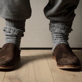 Pair of brown suede slippers on a wooden background.