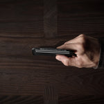 Hand holding a card case on a wooden surface
