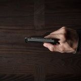 Hand holding a card case on a wooden surface