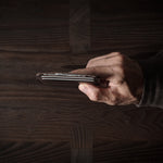 Brown leather card case with cards inside on a dark wood background.