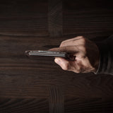 Brown leather card case with cards inside on a dark wood background.