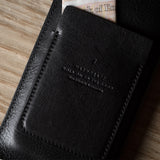 Black leather iphone case with stitching detail on a wooden surface