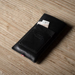 Black leather iphone case with money on a wooden surface
