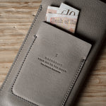 Gray leather iphone case with banknotes on a wooden surface