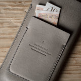 Gray leather iphone case with banknotes on a wooden surface