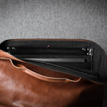 Brown leather laptop bag with a grey interior on a gray background