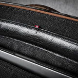 Close-up of a brown leather bag with a zipper and grey interior.