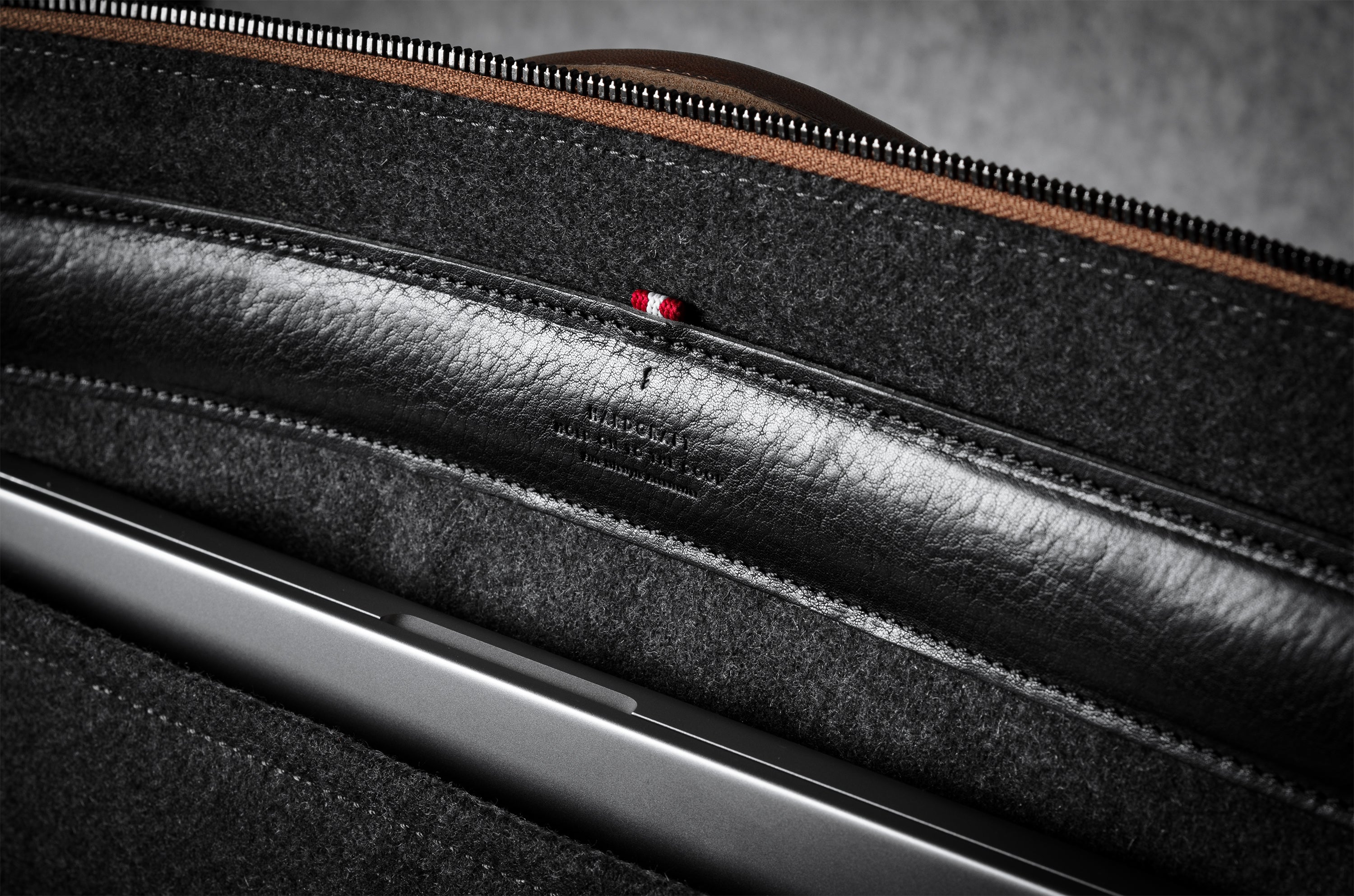 Close-up of a brown leather bag with a zipper and grey interior.
