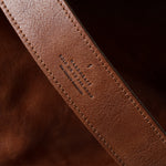 Close-up of a brown leather strap with visible branding on a dark background