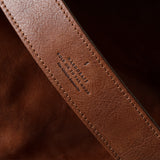 Close-up of a brown leather strap with visible branding on a dark background