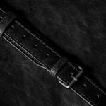 Close-up of a black leather belt on a dark textured surface