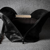 Black leather bag with a book inside on a gray background