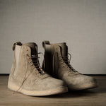 Pair of brown suede boots on a wooden floor with a neutral background