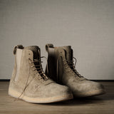 Pair of brown suede boots on a wooden floor with a neutral background
