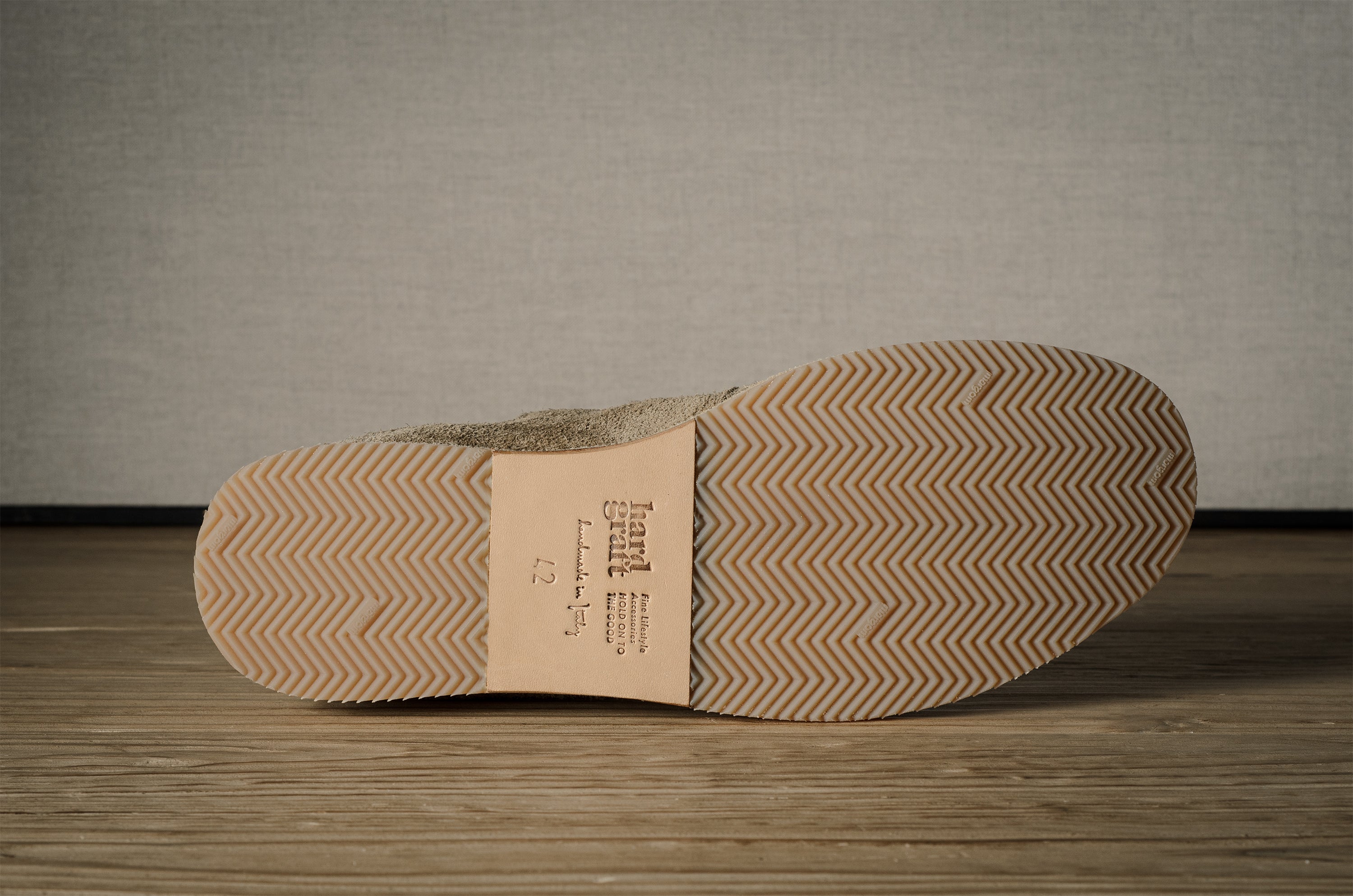 Close-up of a shoe sole with brand label on a wooden floor.