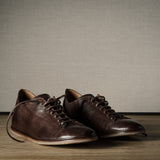 Pair of brown leather shoes on a wooden floor.