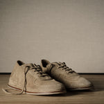 Pair of brown shoes on a wooden floor with a plain background