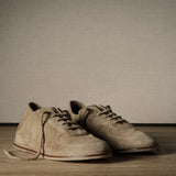 Pair of brown shoes on a wooden floor with a plain background