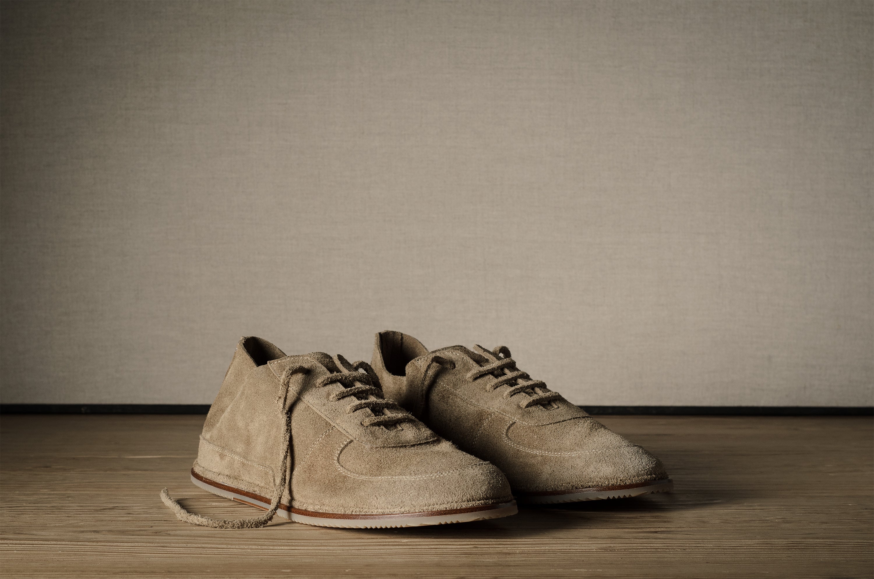 Pair of brown shoes on a wooden floor with a plain background