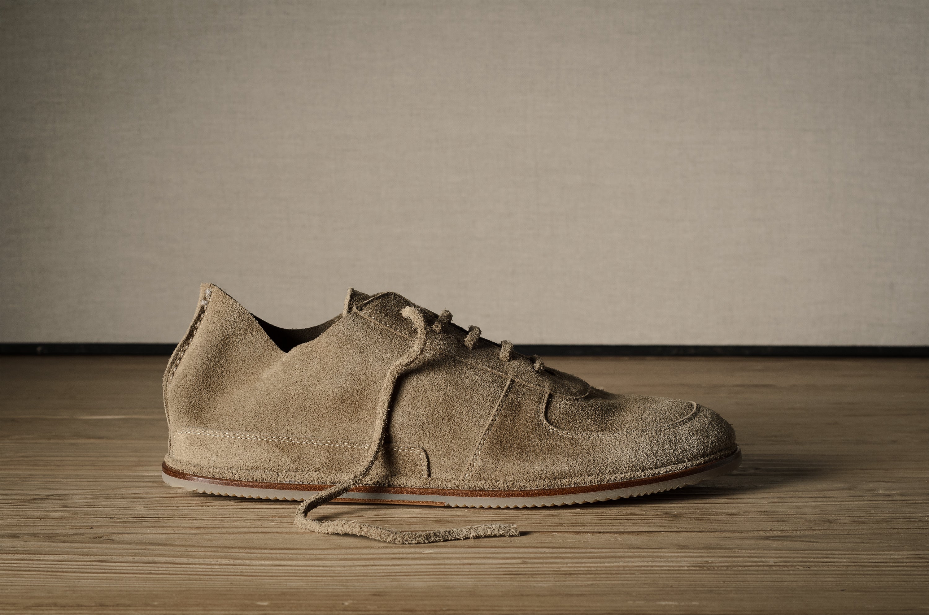 Pair of brown suede shoes on a wooden floor with a neutral background