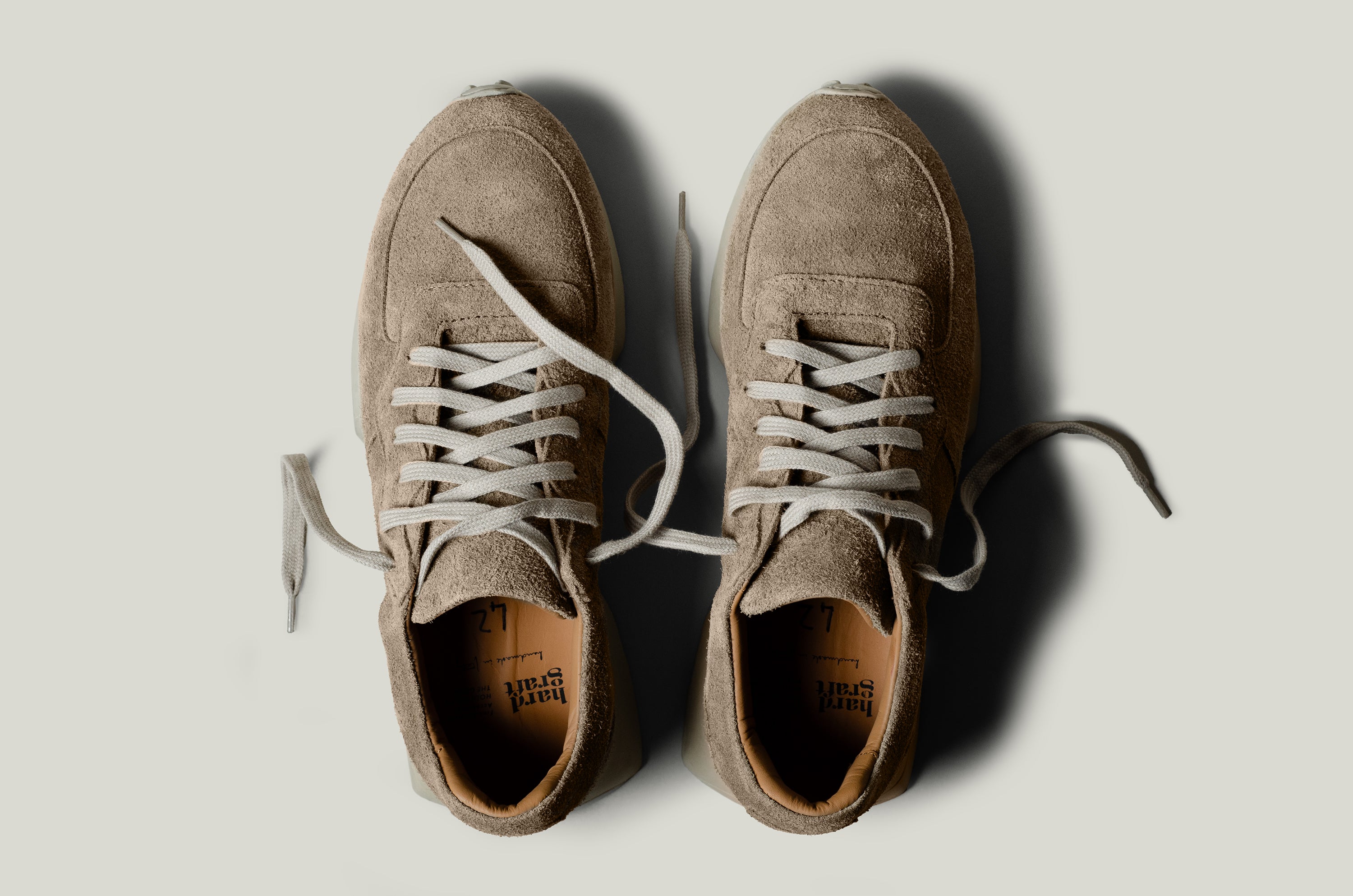Pair of brown suede sneakers on a light gray background