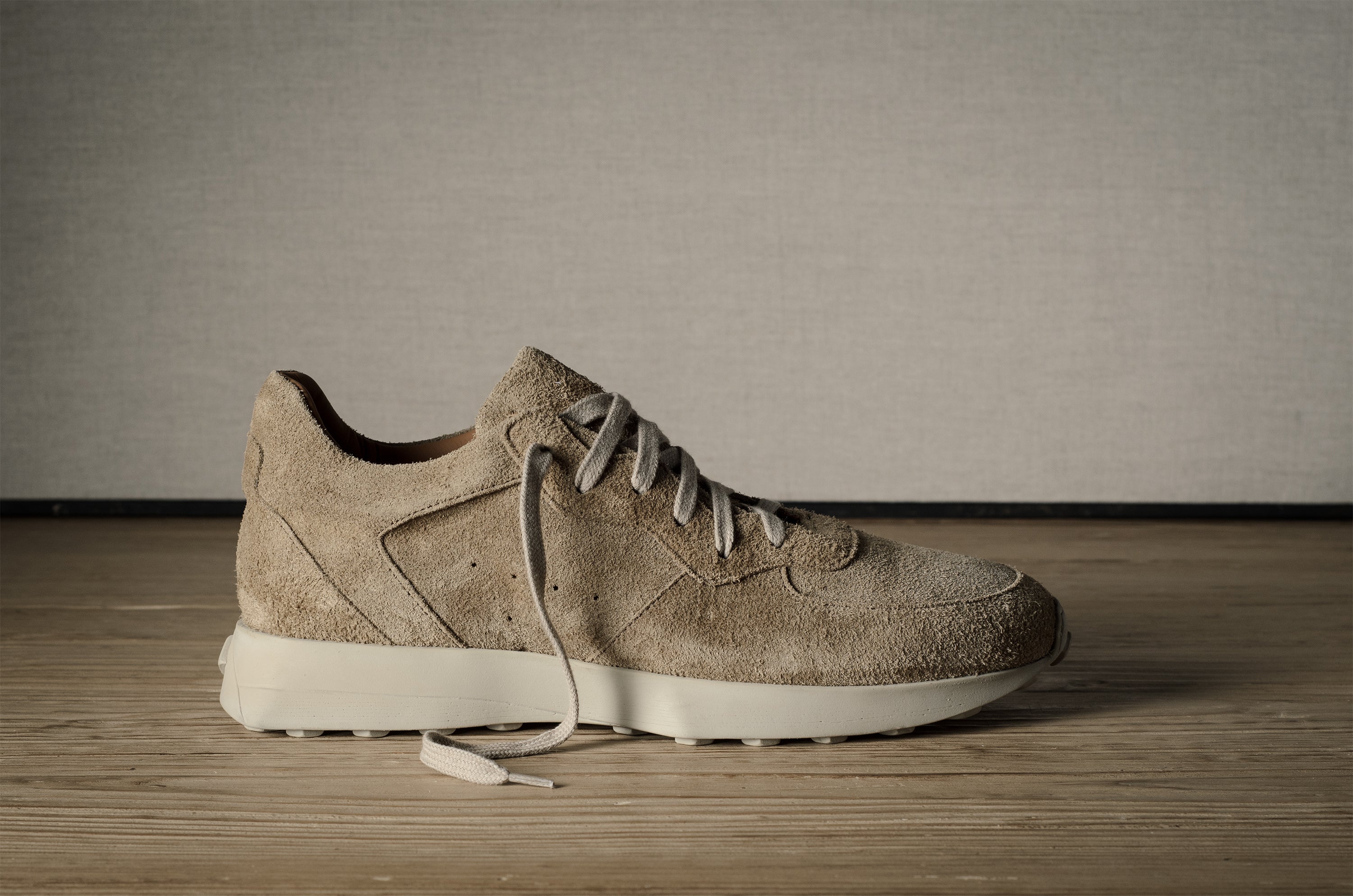 Beige sneaker on a wooden floor with a neutral background