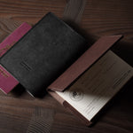 Black and brown leather passport wallet with a passport on a wooden surface