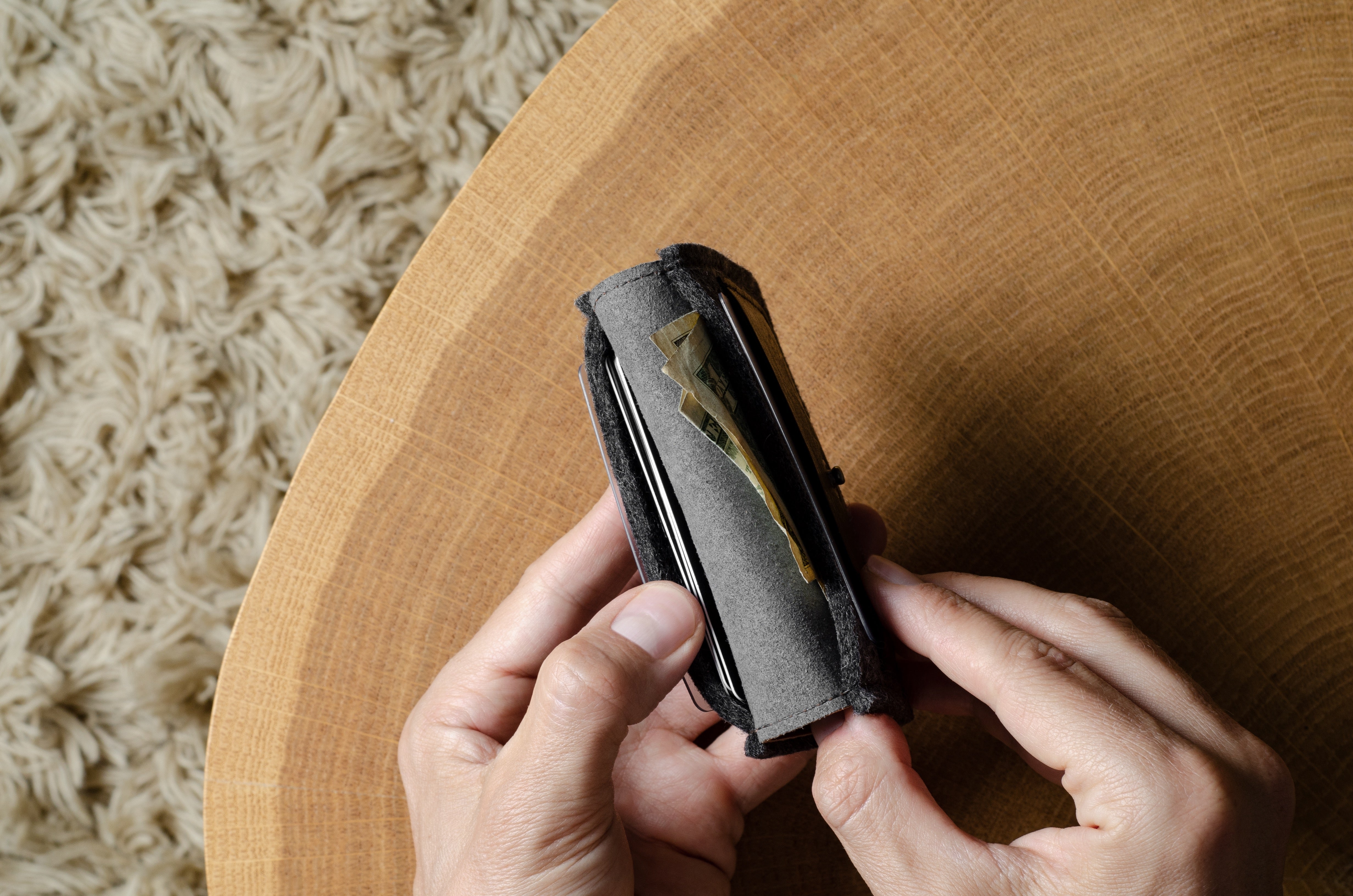 Person holding a compact wallet on a wooden surface with a textured background