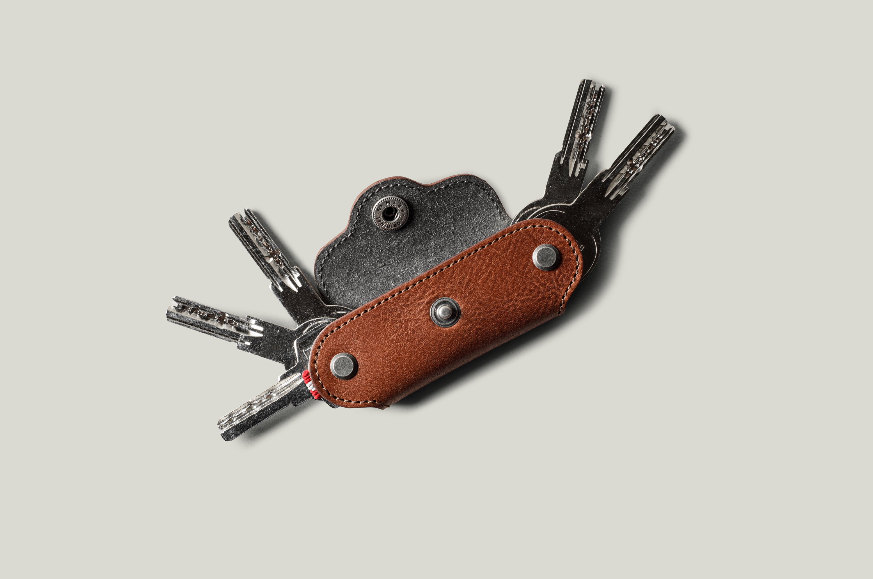 Multi-key pouch made of brown leather on a light gray background