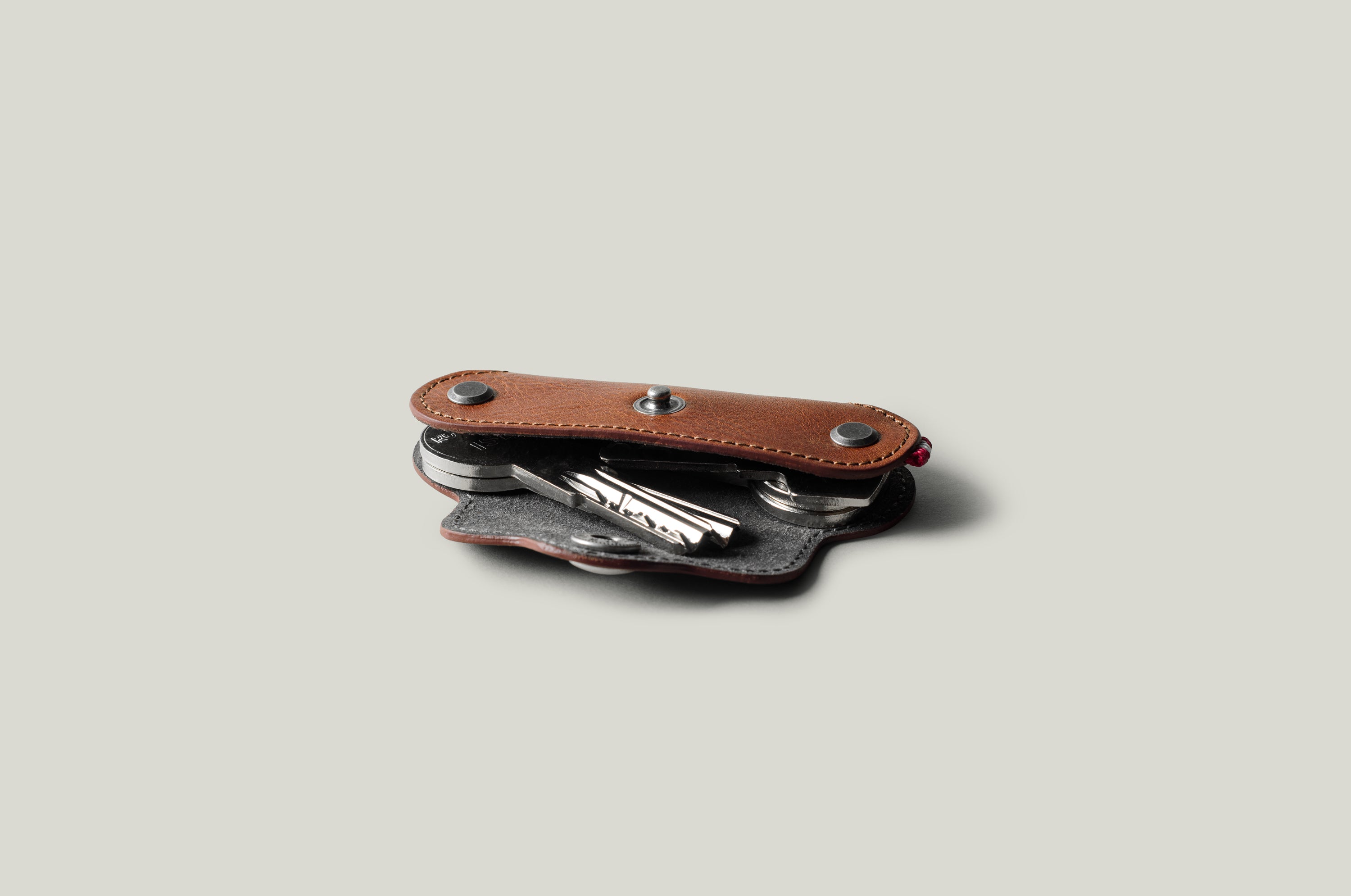 Multi-key pouch made of brown leather on a light gray background