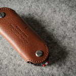 Multi-key pouch made of brown leather on a gray background